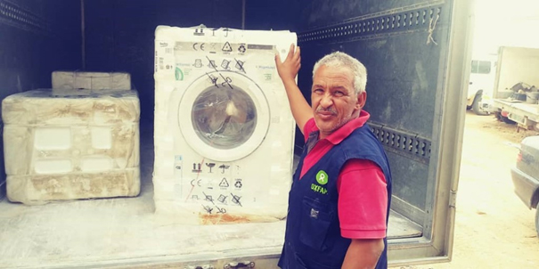 Representant från Belgiska Oxfam på plats i ett av lägren och levererar en tvättmaskin.