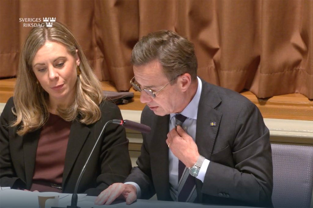 Statsminister Ulf Kristersson lutar sig framåt och läser på en lapp under ett sammanträde i EU-nämnen.