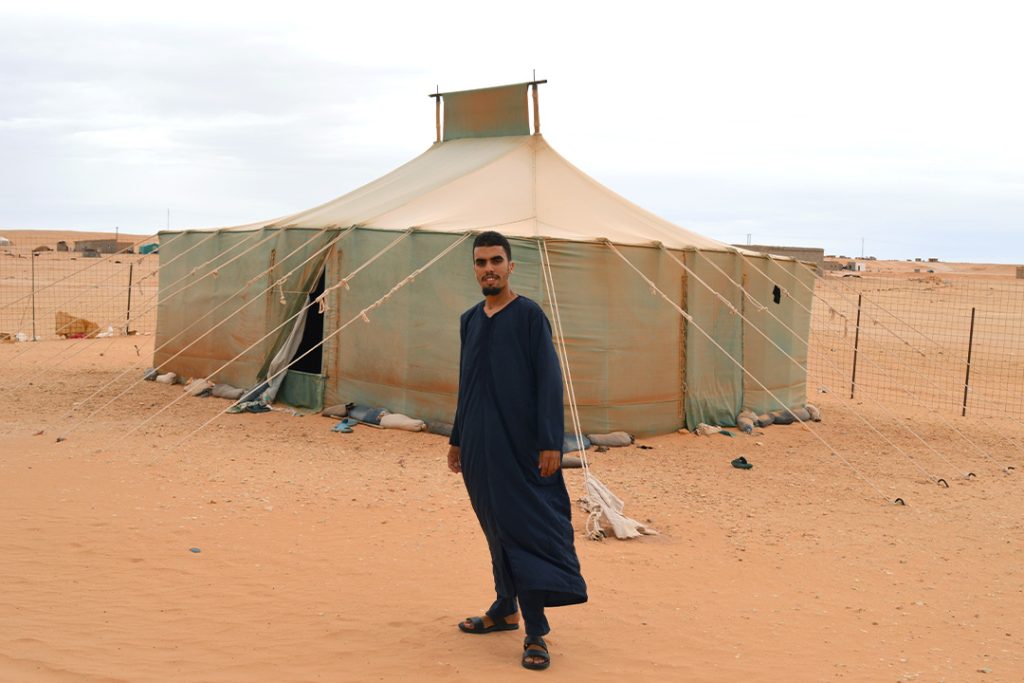Abid står framför ett tält i de västsahariska flyktinglägren. Han tittar rakt in i kameran.