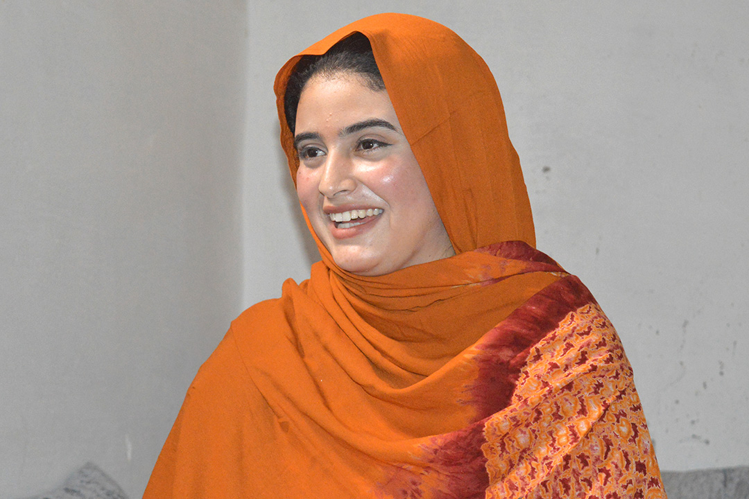 Sallam tittar framåt från sidan. Hon har en traditionell västsaharisk melfa på sig. Hon ler.