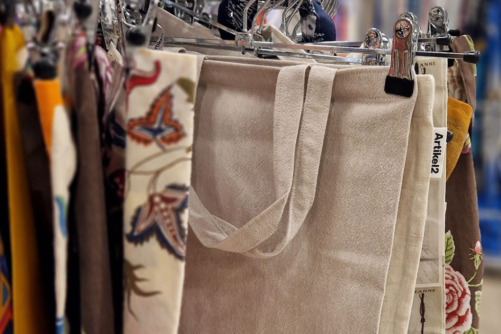 Artikel2 Tygkassar i beige-brun färgskala som hänger på galgar på en ställning